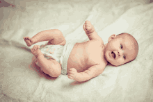 a baby in a diaper is laying on its back with its mouth open