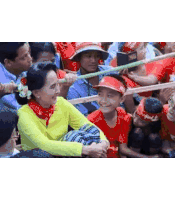 a woman in a yellow shirt is sitting next to a boy in a red shirt in a crowd .