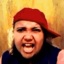 a woman wearing a red hat is making a funny face with her tongue out .