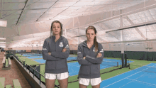 two women standing on a tennis court with their arms crossed and one has a sweatshirt that says ' georgia tech '