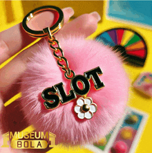 a person is holding a pink keychain that says slot