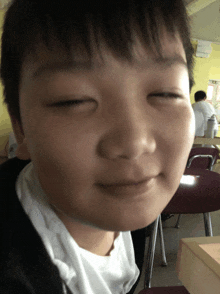 a young boy with his eyes closed is sitting in a classroom