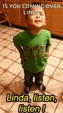 a little boy in a green shirt is standing on a tiled floor and looking up at the sky .