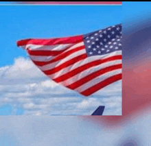 an american flag is waving in the wind in front of a blue sky .