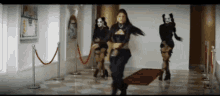 three women are dancing on a red carpet in a hallway .