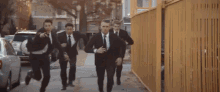 a group of men in suits and ties are running down a sidewalk