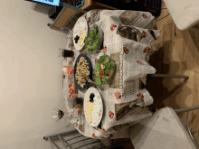 a table with plates of food on it and a strawberry tablecloth