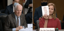 a man in a suit and tie sits at a table next to a woman holding a card