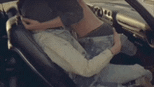 a man and a woman are kissing in a car while the man is holding the steering wheel .