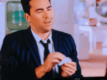 a man in a suit and tie is holding a piece of paper in front of a samsung tv