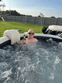 a bald man is in a hot tub holding a beer