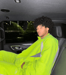 a young man in a neon yellow nike outfit sits in the back seat of a car