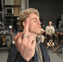 a man with a ring on his finger is blowing a kiss in a studio .