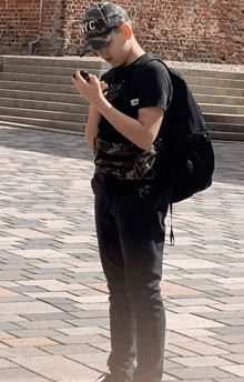 a young boy wearing a nyc hat looks at his phone