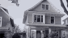 a black and white photo of a house with a lot of windows and a tree in the background .