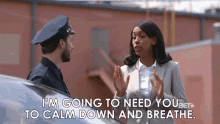 a man in a police uniform is talking to a woman in a business suit while standing next to a car .