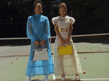 two women standing next to each other on a tennis court with a yellow bag with the letter f on it