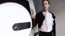 a man standing in front of a white mercedes logo