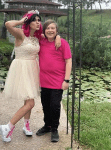 a woman in a white dress and a boy in a pink shirt pose for a picture