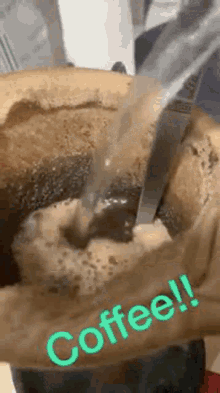 a close up of a person pouring water into a cup of coffee with the word coffee written on it .