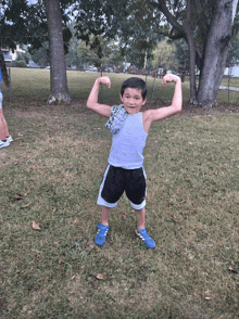 a young boy is flexing his muscles in the grass