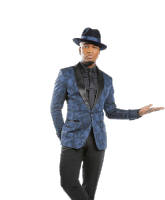 a man in a blue tuxedo and black hat is standing with his hand outstretched