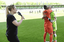 a woman is holding a microphone and talking to two soccer players one of whom has the number 11 on his jersey