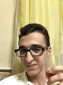 a young man wearing glasses holds a glass of wine