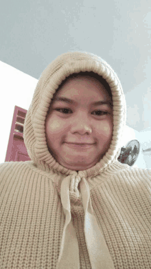 a woman wearing a tan sweater with a hood