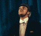 a man in a hat and bow tie is making a face