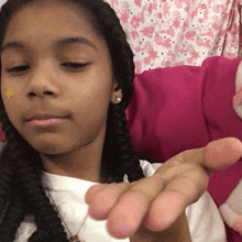 a young girl with a yellow star on her face is sitting on a pink couch