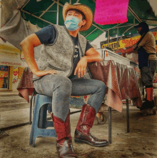 a man wearing a mask and cowboy boots sits under a sign that says ' carniceria ' on it