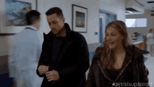 a man and a woman are standing in a hospital hallway .