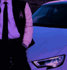 a man in a suit and tie is standing in front of a white car with the letter a on his vest