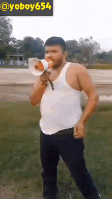 a man in a white tank top is holding a megaphone in front of a sign that says @ yoboy654