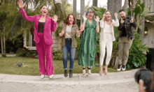 a group of people are posing for a picture in front of a house while jumping in the air .