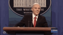 a man in a suit and tie is standing at a podium in front of a sign that says the white house