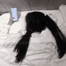 a woman laying on a bed holding a cell phone