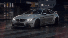 a white bmw is driving down a wet street at night .