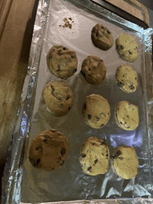 a bunch of chocolate chip cookies on a foil covered pan