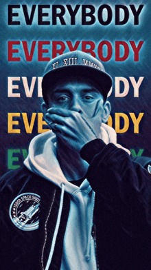 a man covering his mouth in front of a poster that says " everybody "