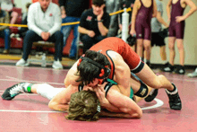 two wrestlers are wrestling on a mat with the word nike on the bottom