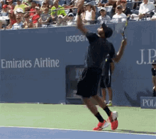 a tennis player is jumping in the air while holding a tennis racquet in front of an emirates airline banner