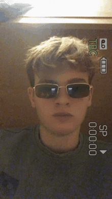 a young man wearing sunglasses is being recorded by a camera with tbc written on the screen