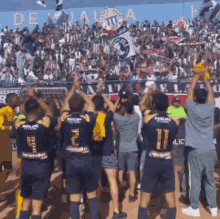 a group of soccer players are raising their arms in the air in front of a crowd at a stadium