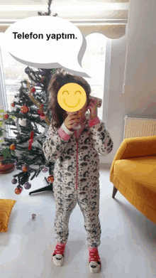 a little girl standing in front of a christmas tree with a speech bubble above her that says telefon yaptim