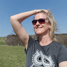 a woman wearing sunglasses and a gray shirt with an owl on it