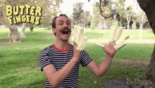 a man in a striped shirt is holding a piece of butter in front of a sign that says butter fingers