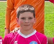 a young boy wearing a pink soccer jersey is posing for a picture with his teammates .