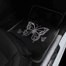 a black car mat with a butterfly on it and the word mercedes on the side